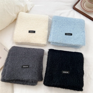Detail view of four-color knit scarves showing soft texture and BOWLOW woven label
