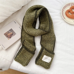 Detailed close-up of moss green ribbed knit scarf texture with a white fabric brand label