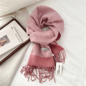 Macro detail of pink herringbone lamb wool scarf with fringes on a cozy white bed