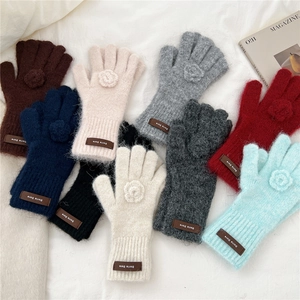 Detailed top view of eight colorful knitted gloves with 3D floral accents and leather tags