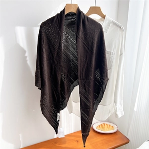 Detail of knitted openwork triangle shawl in dark brown with elegant wave pattern