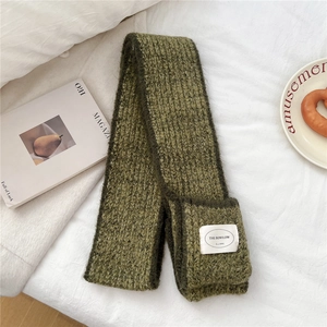 Detailed close-up of grass green knit scarf featuring a side pocket and woven brand label