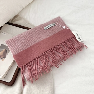 Detailed macro view of 100% lamb wool pink herringbone scarf with elegant long fringe tassels