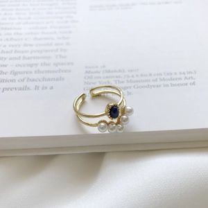 Detail of vintage gold pearl ring with blue gemstone on artistic book background