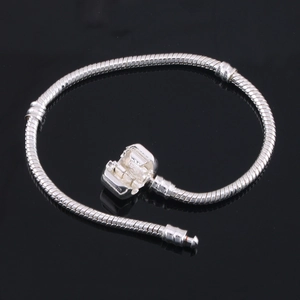 Detail of silver snake chain bracelet with barrel clasp on a reflective black background