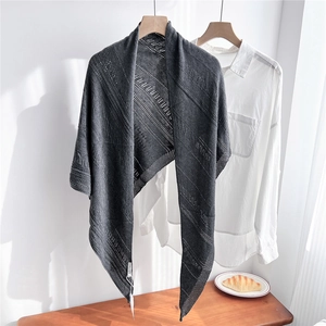 Detail of dark grey knitted shawl featuring geometric openwork pattern and light texture