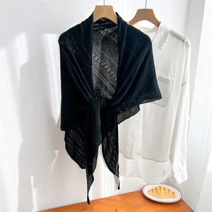Close-up of black hollow knit shawl on a wooden hanger showing the mesh texture