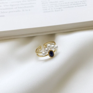Detail of vintage gold-plated silver ring with blue gemstone and white pearls on silk