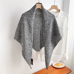 Close-up of marled gray knitted wool triangle shawl with thick texture on a wooden hanger