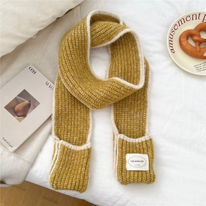 Detail of chunky knit mustard yellow scarf with large pockets and contrast white stitching