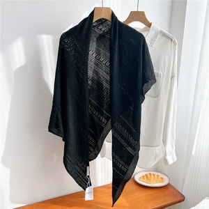 Detail of black knitted shawl featuring hollow stripe design and soft fabric texture