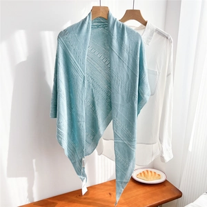 Detail shot of light blue knitted shawl with openwork pattern on a wooden hanger