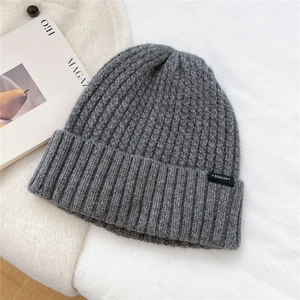 Close-up of grey ribbed knit beanie texture and rectangular logo patch detail