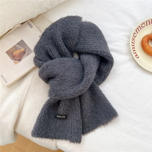 Close-up detail of soft wool blend scarf texture with black brand woven label