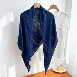 Detail view of a navy blue hollow knit triangle shawl draped on a wooden hanger