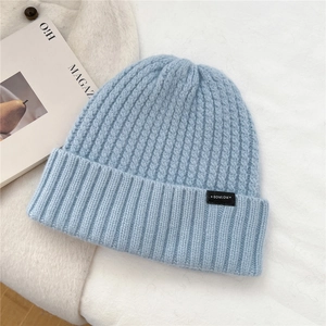 Close-up of light blue wool knit beanie with rib pattern and BOWLOW brand label