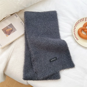 Detail of soft dark grey wool blend scarf featuring a woven brand label and plush texture