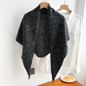 Detailed close-up of a black and white knit triangle scarf texture with hanging tag