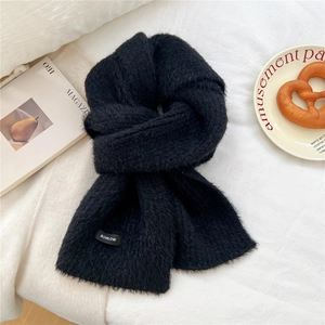 Close-up of fluffy black wool blend knit scarf showing soft texture and woven label