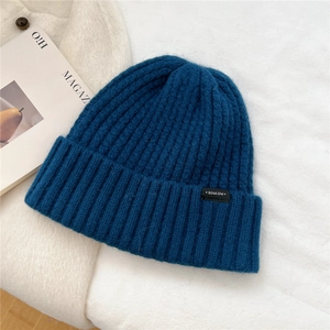 Close-up of blue wool knit beanie showing thick ribbed texture and brand side label