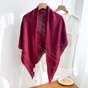 Close-up of wine red knitted triangle shawl with hollow patterns and product tag