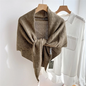 Close-up of earth tone wool knit triangle shawl with textured weave and brand tag