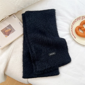 Close-up of thick black wool blend knit scarf with premium BOWLOW brand logo patch