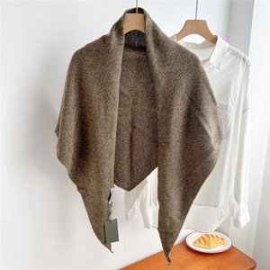 Close-up of wool knit triangle scarf texture with laundry tag and wooden hanger