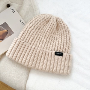 Close-up of thick ribbed knit wool beanie in cream white with black logo label