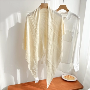 Close-up of cream knit shawl showing intricate hollow diamond patterns and fine texture
