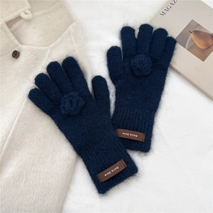 Detailed macro view of dark blue plush knitted gloves with decorative 3D floral accents