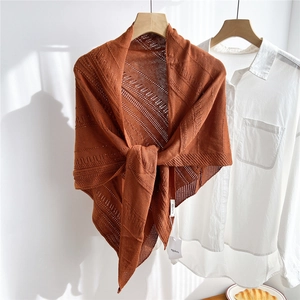 Close-up of caramel knitted triangle shawl with elegant hollow out geometric patterns