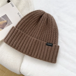Close-up of thick ribbed knit texture and brand label on a brown wool beanie