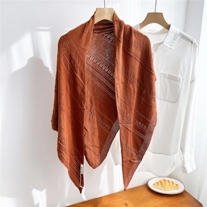 Close-up of caramel knit triangle shawl with delicate hollow pattern on a wooden hanger