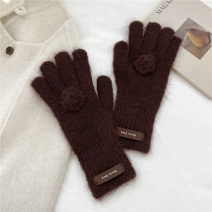 Close-up of plush dark brown knit gloves with soft floral accents and brand tag