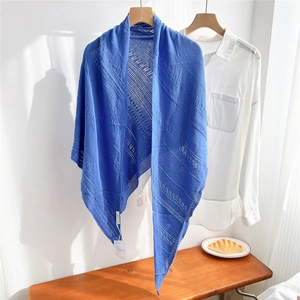 Detail view of royal blue knitted shawl with openwork stripe pattern on wooden hanger