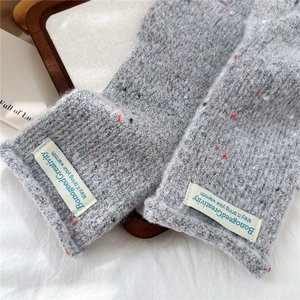 Detailed texture of grey knit fingerless gloves with custom label and soft yarn finish