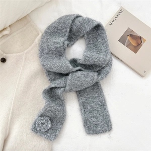 Detail showing the gray knit scarf texture with a handmade crochet flower decoration