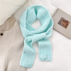 Detail of mint green knit scarf showing soft texture and 3D crochet flower ornament
