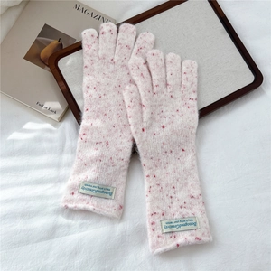Detail of pink knitted winter gloves with red polka dots and premium woven brand label