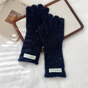 Close-up of navy blue flecked knit gloves with white logo patch on a wooden tray