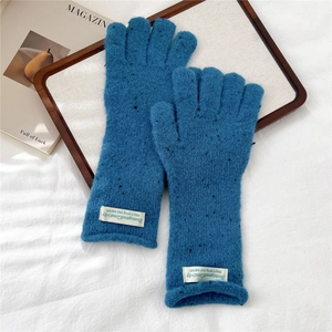 Macro shot of navy blue knitted gloves with thick texture and white fabric label detail
