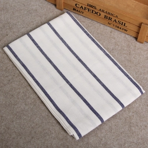Detail of a white cotton linen napkin with thin blue stripes on a soft background