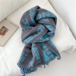 Détail de l'écharpe en maille bleu-gris avec jacquard de lettres et franges douces