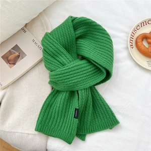 Dettaglio della sciarpa in maglia verde brillante con trama a coste ed etichetta nera