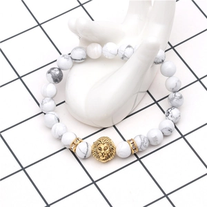 Detail shot of white marble beads and gold lion head charm on a hand display