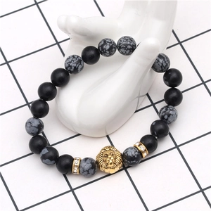 Detail shot of black onyx beaded bracelet with golden lion head charm on hand model