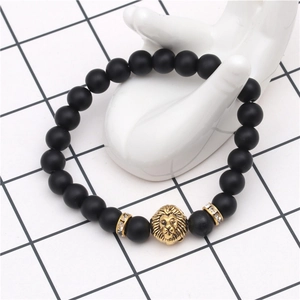 Detail of matte black beads with a golden lion head and crystal spacers on a hand model