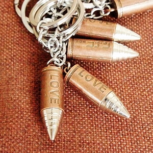 Detailed close-up of bullet-shaped metal keychain with Love and Conan engravings
