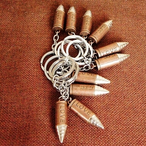 Detail view of copper metal bullet keychains with Love and Conan engravings on fabric